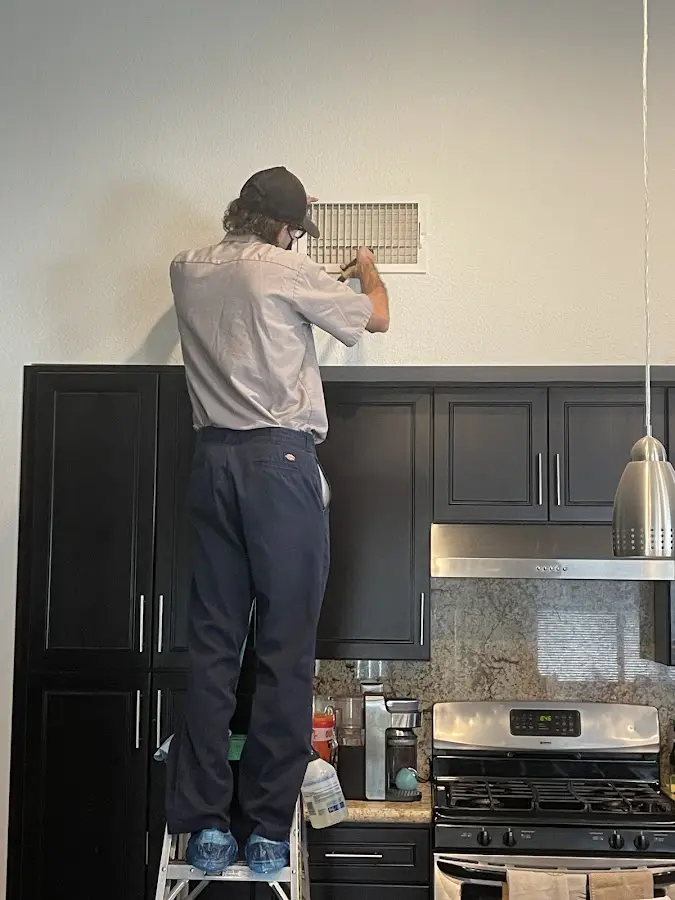 Technician inspecting an air vent during HVAC service in Sunrise